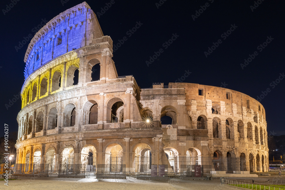 Colosseum at night, Rome, Italy, lit with the yellow and blue colors of the Ukrainian flag.