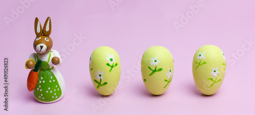 Easter mom rabbit and three eggs on a pink background