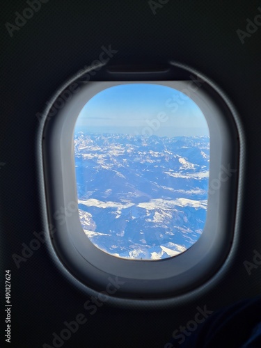 Panorama of the snow capped Alps in the window of an airplane flying over them
