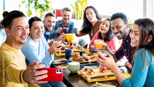 Friends taking selfie on breakfast time drinking juices and eating cakes - People having fun at fashion cafeteria - Life style concept with happy men and women at cafe bar - Selective focus on sides