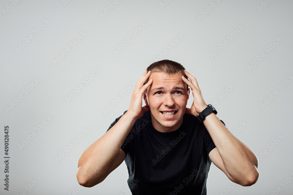 Overworked man has headache, feels tired Young man holds fingers on temples Overworked man has headache, feels tired Young man holds fingers on temples