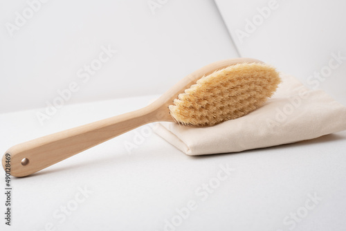 Massage brush for body. Dry lymphatic drainage massage. Wooden brush made of cactus and boar fiber n a light background.
