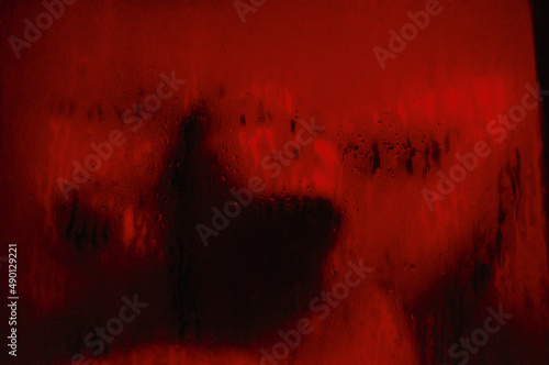 woman showering behind screen with sensual red light photo