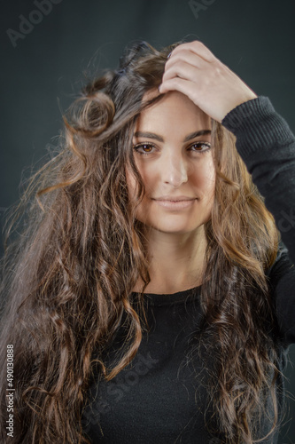 Portrait of a beautiful young woman who tries to fix her very long hair with her hand