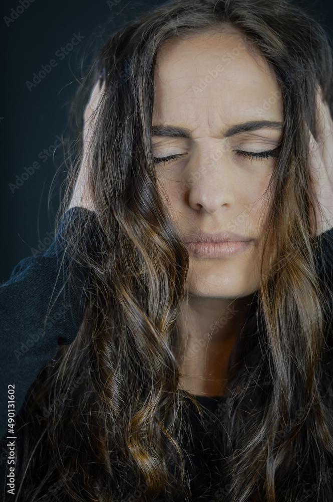 Portrait of a beautiful young woman with long hair with her hands in her hair with her eyes closed and an expression of intense pleasure Portrait of a beautiful young woman with long hair with her hands in her hair with her eyes closed and an expression of intense pleasure