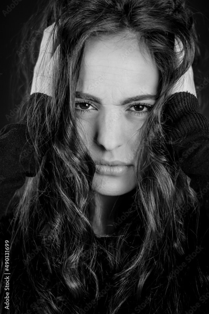 Black and white portrait of a beautiful young desperate woman with her head in her hands and looking at the camera Black and white portrait of a beautiful young desperate woman with her head in her hands and looking at the camera