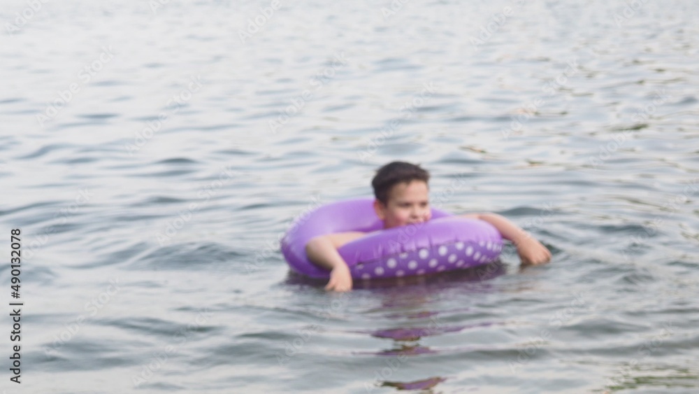 Kid on beach with swimming circle. Boy swimming in sea. Children and holiday concept