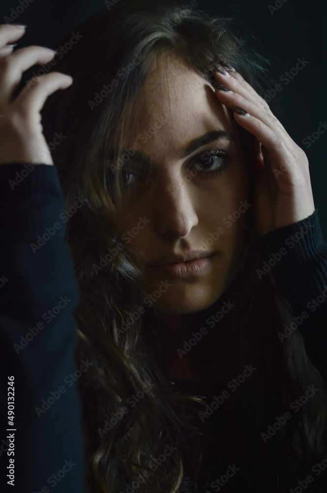 Fototapeta premium Portrait of a beautiful young woman who tries to hide her face with her hand and go unnoticed