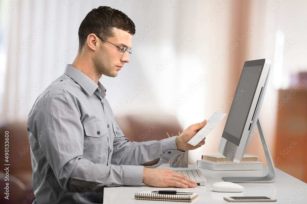 Smiling business man working on computer at the home office. Smiling business man working on computer at the home office.