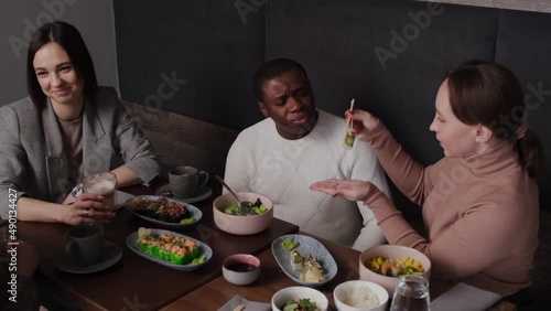 Girl feeding African American man sushi