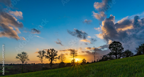 An approaching rainstorm is beautifully lit by the sun slowly setting over the rolling countryside near Montpinchon in Normandie  France