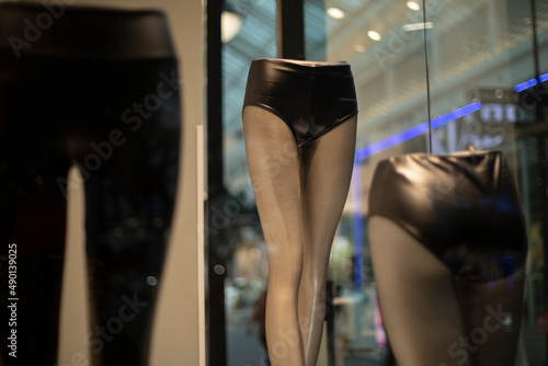 Women's mannequin shopping mall. Window of clothing store. Dummy of leg. Black clothes of modern style.