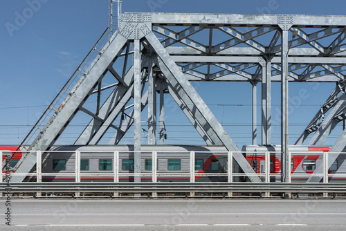 Travel by train. The train rides on a beamed metal bridge. Metal construction.