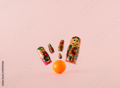 Obraz na plátně Russian dolls matryoshka or babushka as the pins flying from the strike of the orange bowling ball on a pink background