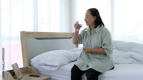 Senior asian woman holding pill and glass of water, taking medicine from headache, stomach pain or taking vitamins.