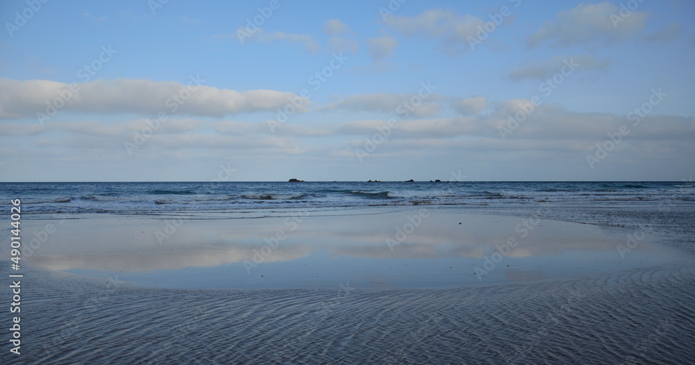Sandy beach with the sky reflected on the water at low tide, Caleta de Famara, Lanzarote Island, Spain