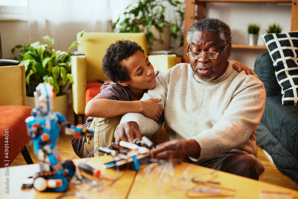 A grandfather showing his grandchild how to make a robot while sitting at home. A grandfather showing his grandchild how to make a robot while sitting at home.
