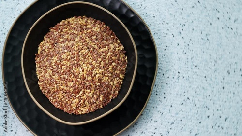 Mixed golden and brown flaxseed in bowl. Linseed seed, top view, table spin.