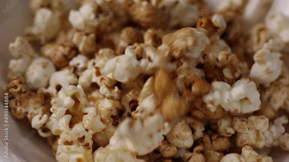 Close-up tossing popcorn into a bowl. Shot 4K Slow Motion. Caramel flavour. Close-up tossing popcorn into a bowl. Shot 4K Slow Motion. Caramel flavour.