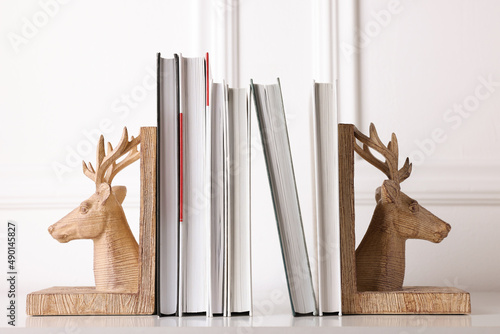 Foto Wooden deer shaped bookends with books on table indoors