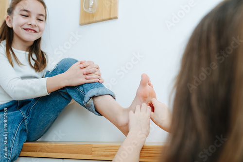 Foto Confident tween girl sitting on a corridor shelf giving her foot to be tickled
