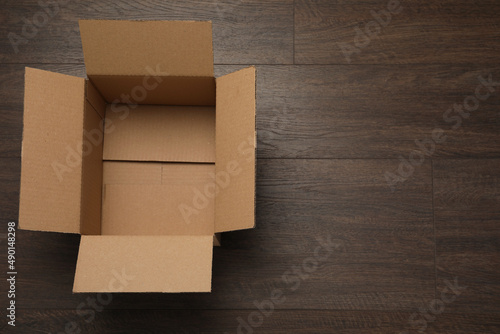 Empty open cardboard box on wooden table, top view. Space for text © New Africa