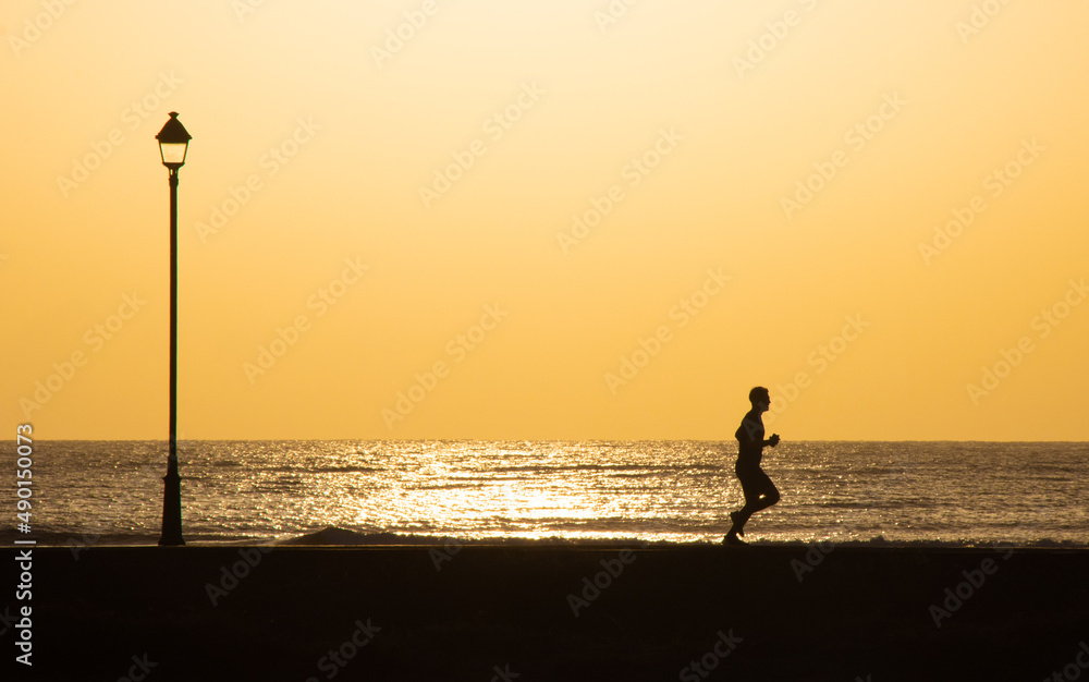 silhouette of a person running on the beach path
