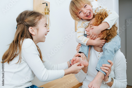 Wallpaper Mural Happy sister ticklig little boy's feet, he is sitting on his mom's shoulders Torontodigital.ca