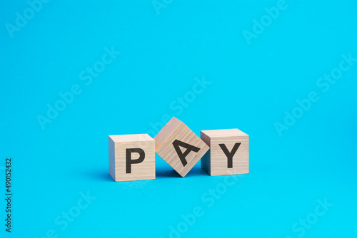 pay - text on wooden blocks, business concept, blue background