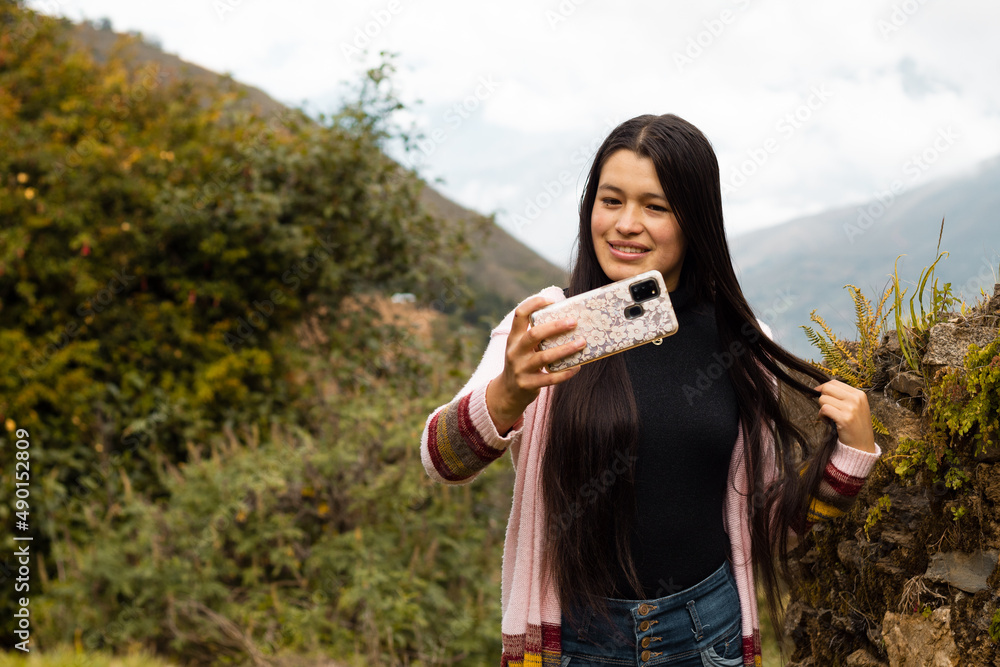 Fototapeta premium Mujer joven con cabello largo y negro tomando selfies en un parque sonriente