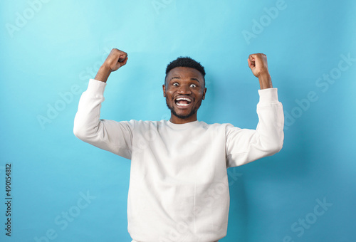 Portrait of a cheerful young African American man shouting with his hands raised in a sign of success