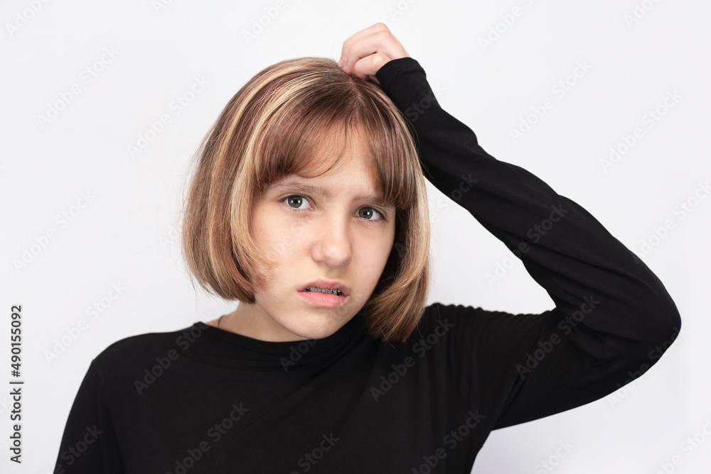 A teenage girl with braces on her teeth, suffers, holds her head