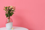 Vase with beautiful roses on table near pink wall