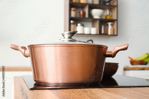 Shiny cooking pot on stove in light kitchen, closeup