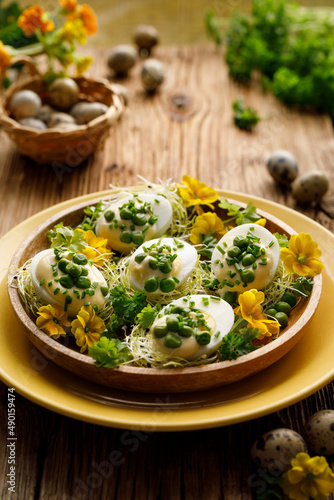 Photography Hard-boiled eggs divided into halves with the addition of mayonnaise and green peas sprinkled with fresh chives on a decorated plate, focus on the egg inside