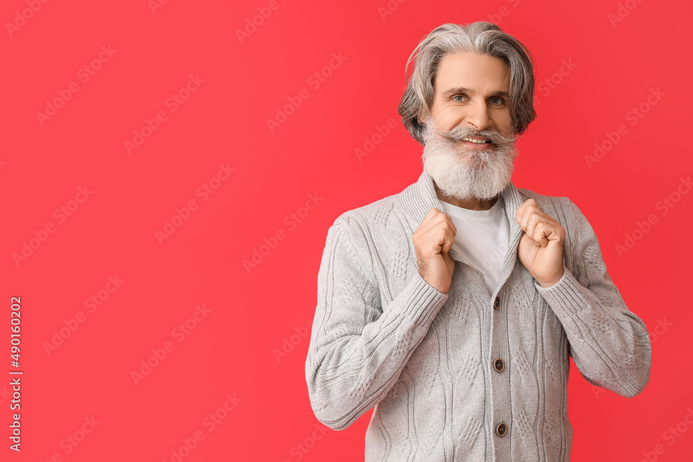 Handsome senior man in knitted sweater on red background Handsome senior man in knitted sweater on red background