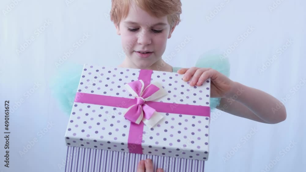 A teenage girl in a beautiful evening dress. The child opens the box with the gift. The emotions of surprise and happiness from the surprise in the box A teenage girl in a beautiful evening dress. The child opens the box with the gift. The emotions of surprise and happiness from the surprise in the box