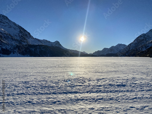 Snowy field and mountains in the background with the bright sun shining photo