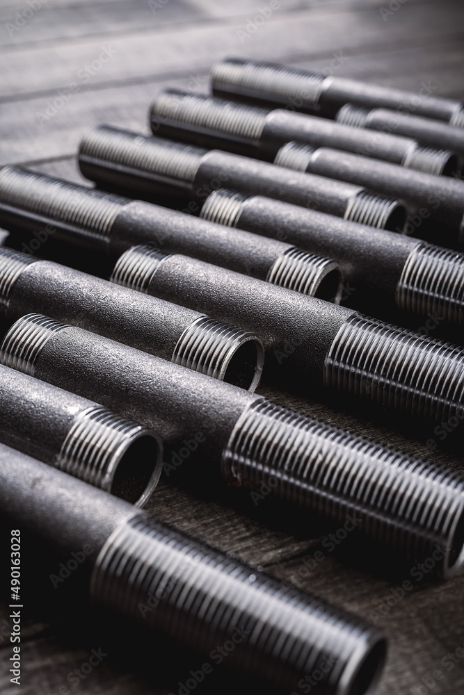 Cast iron pipes and fittings of different shape and forms, laying on a rustic wooden table Cast iron pipes and fittings of different shape and forms, laying on a rustic wooden table