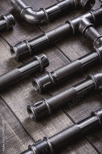 Cast iron pipes and fittings of different shape and forms, laying on a rustic wooden table