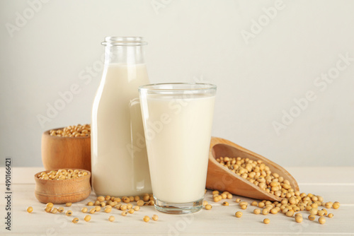 Fresh soy milk and grains on white wooden table