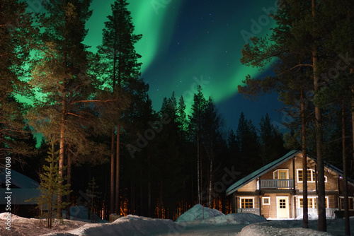 Foto Polarlichter über den Bäumen einer Wohnsiedlung bei Levi in Finnland