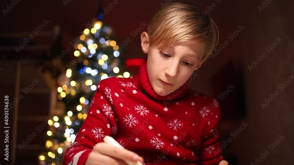 a child in a red sweater draws with markers on the background of Christmas lights a child in a red sweater draws with markers on the background of Christmas lights