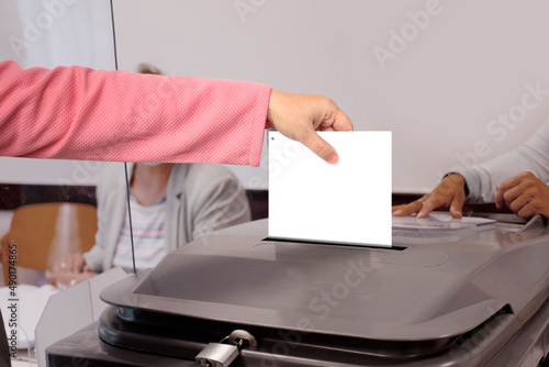 female voter throws a ballot paper into a gray ballot box at a polling station in Germany, hand with paper close-up, concept of state party elections, referendum © kittyfly