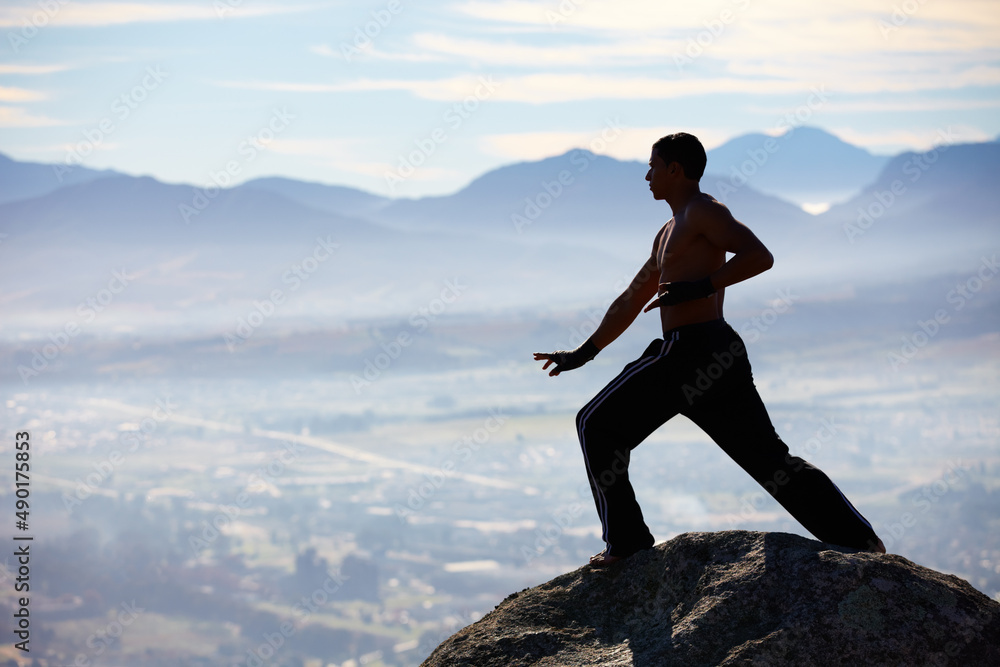 Mountain training is the best. A male kickboxer high up on a mountain top to practice. Mountain training is the best. A male kickboxer high up on a mountain top to practice.