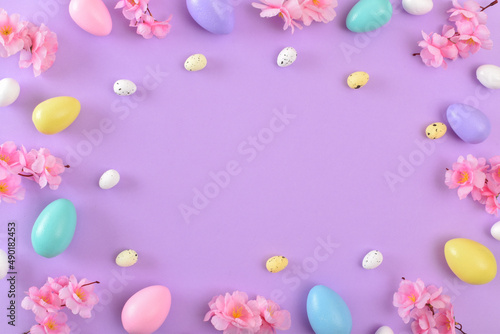 Background with Easter colored eggs on a purple background. Spring background for the Easter holiday. Copy space. Flat lay  top view.