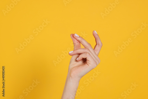 Woman snapping fingers on yellow background, closeup of hand photo