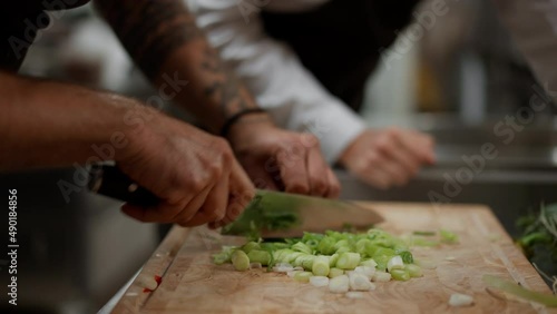 Unrecognizable chef cutting vegetables indoors in restaurant kitchen.