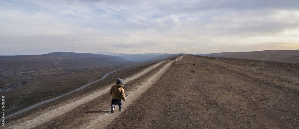A small child on a long trampled road. An endless horizon into the unknown.