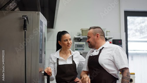 Chef teaching cook how to use combi oven indoors in restaurant kitchen. photo